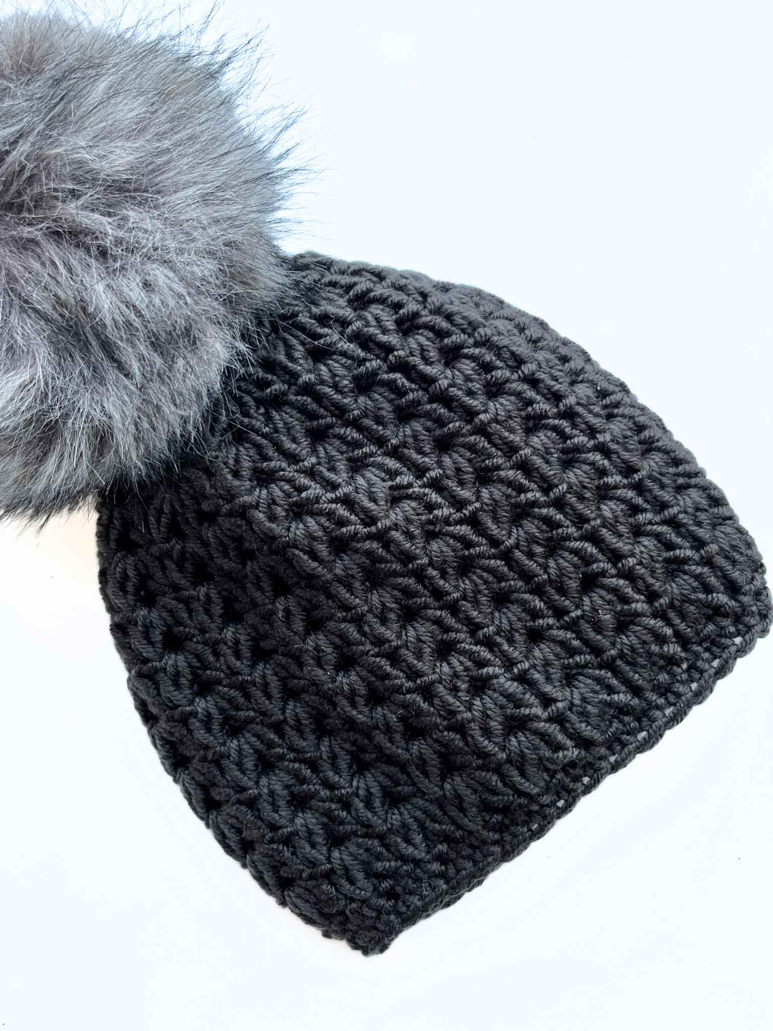 dark gray crocheted hat with a pom pom on the top